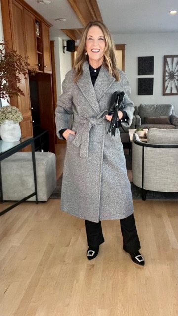 Grey double breasted wrap coat, coated black jeans, pouch style clutch and ankle boots.