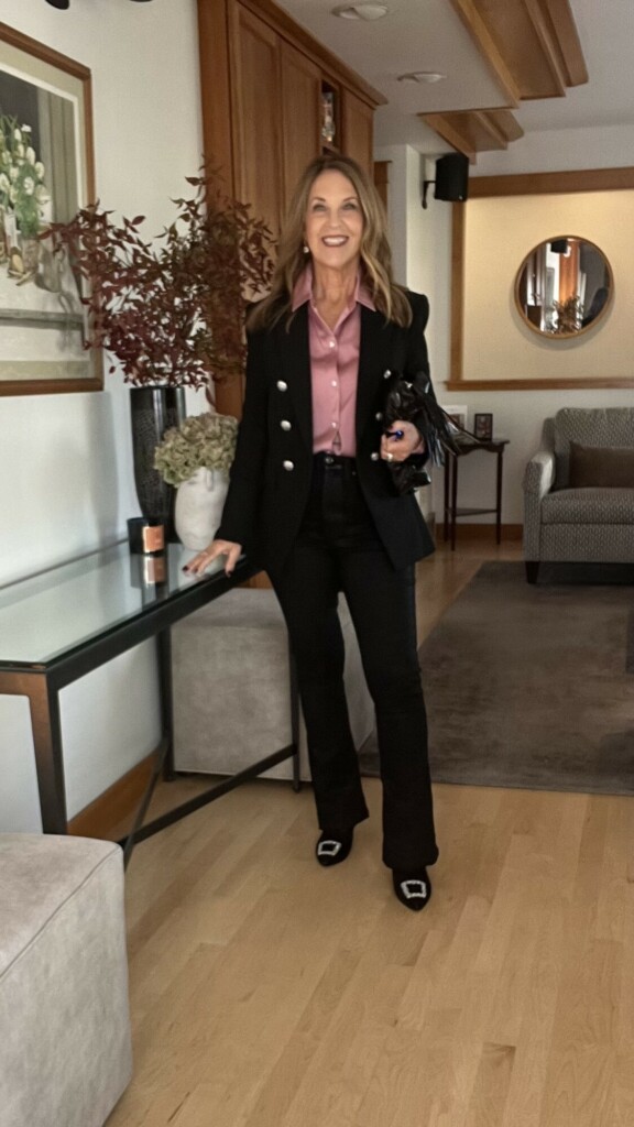 Coated black jeans, pink silk button-up shirt with crystal buttons, Veronica Beard Miller blazer, black booties with crystal details, and pouch-style clutch