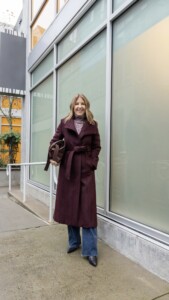 Bordeaux color longline wool coat, turtleneck, wide-leg jeans, boots and fold-over bag. 