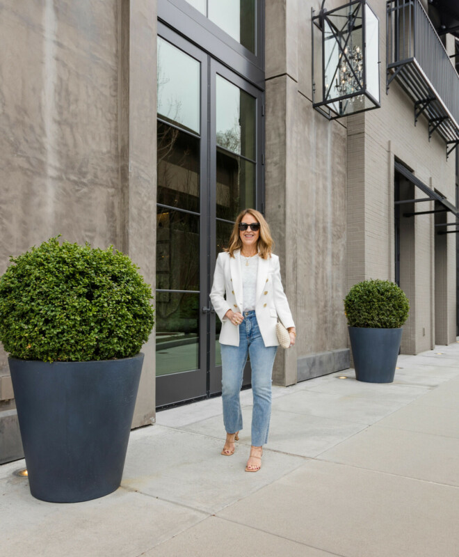 Mid rise, bootcut jeans for spring, white blazer, t-shirt, sandals and clutch.