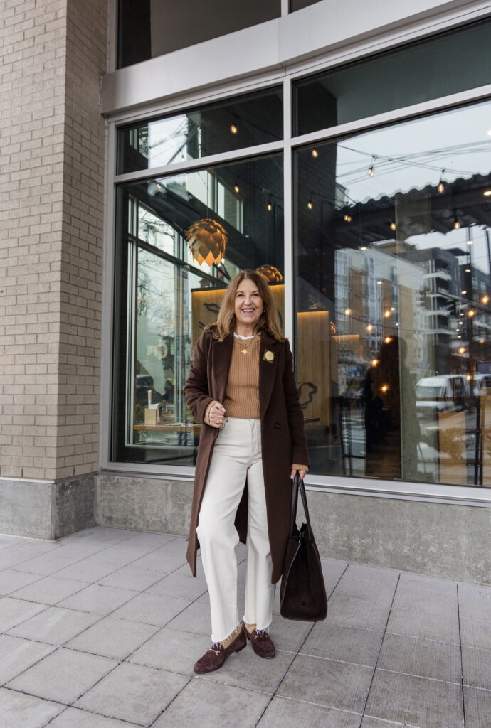 ecru jeans and brown loafers and brown overcoat